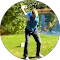 A young golfer swings a club on a sunny golf course.