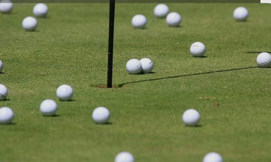 Numerous golf balls scattered around a hole on a green putting surface.